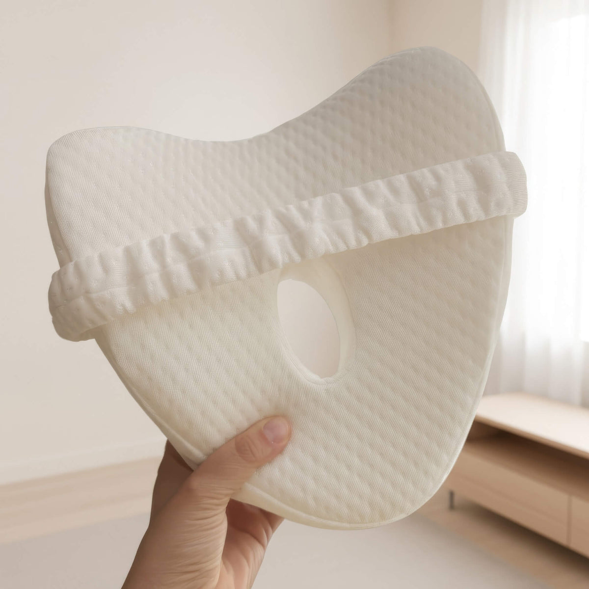 Hand holding the EverComfort ComfortCurve knee pillow, showing its contoured shape and size