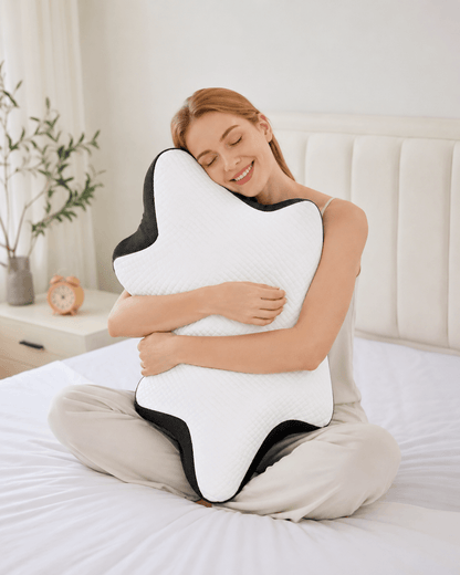 Woman sitting on a bed holding the EverComfort NeckEase pillow